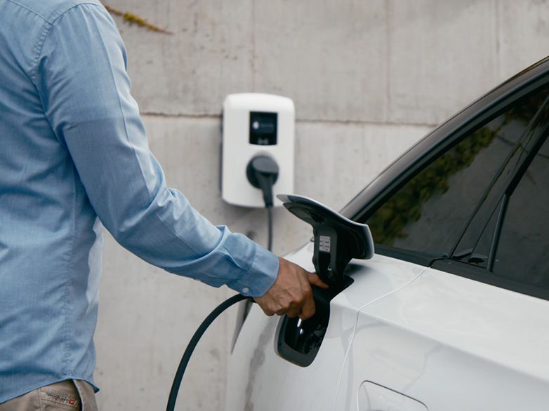 Osoba nabíjející auto u wallboxu