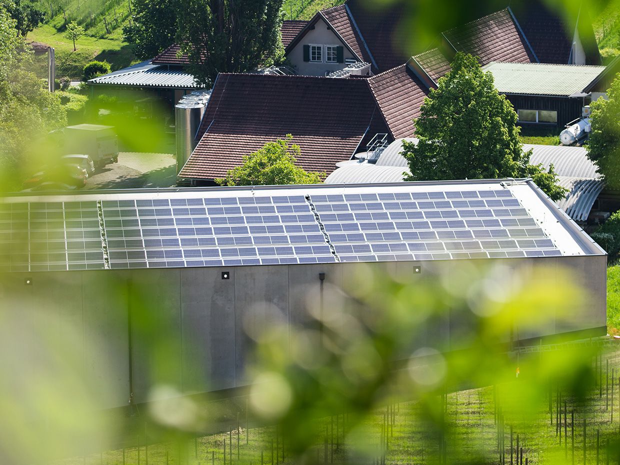 Fotovoltaický systém na střeše před skupinou domů