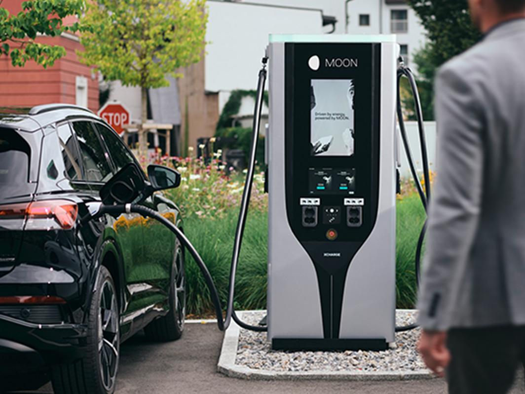 Osoba jde směrem k nabíjecí stanici