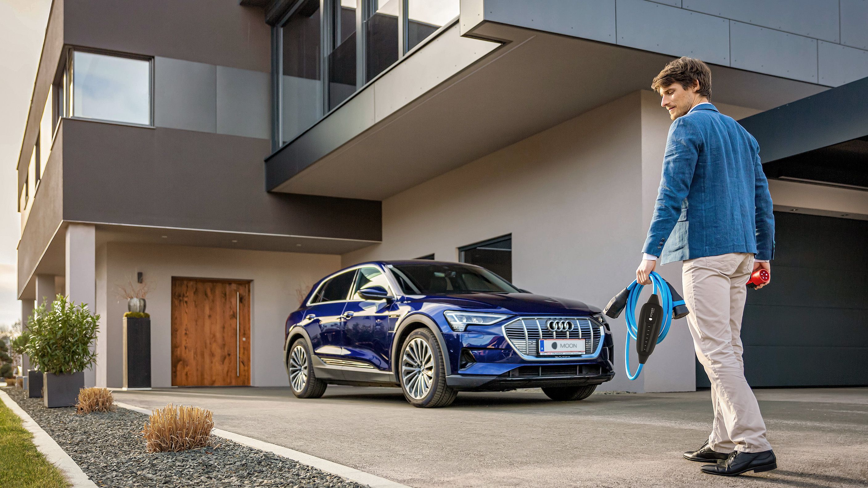 Muž kráčí k autu poblíž domu s kabelem v ruce