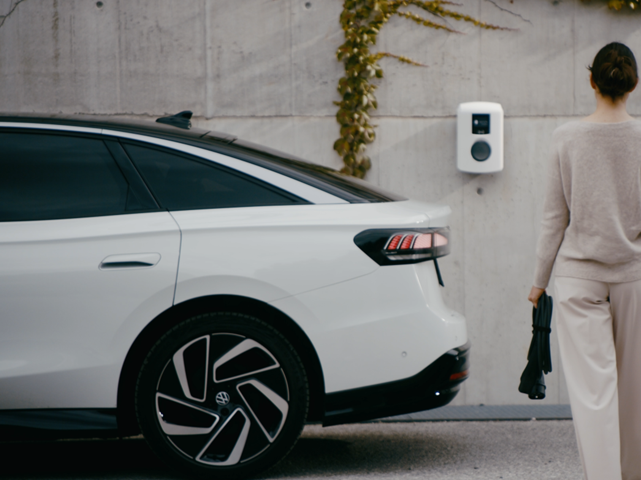 Žena jde k nabíjecí stanici na zdi