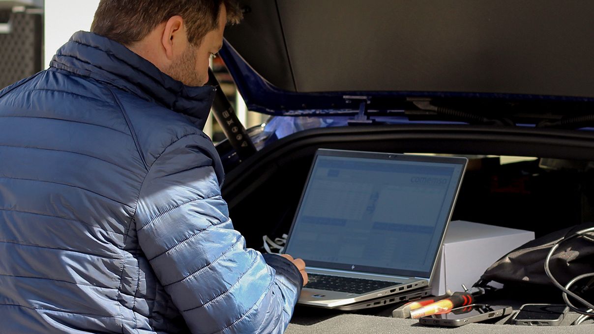 Muž s notebookem stojí na krytu kufru